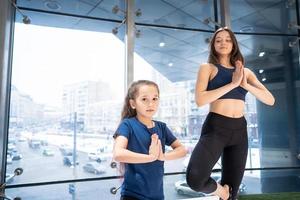 jeune mère adulte et petite fille pratiquant ensemble le yoga photo