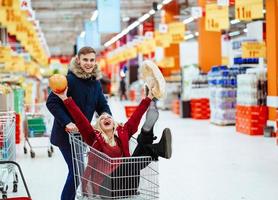 jeune beau mec monte une fille dans un supermarché dans un chariot photo