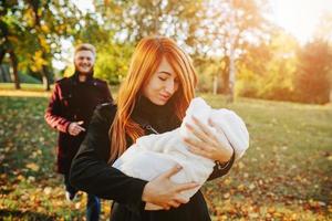 jeune famille et fils nouveau-né dans le parc d'automne photo