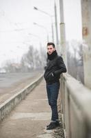 un homme vêtu d'un jean et d'une veste se tient près de la route principale par temps de brouillard photo