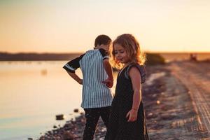 deux enfants marchent le long de la plage, soirée d'été photo