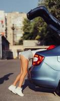 la fille regarde quelque chose dans le coffre d'une voiture photo