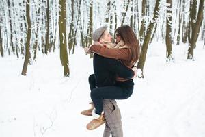 le gars tient la fille sur les mains dans le parc à neige photo