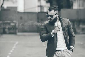 homme à barbe fume une cigarette électronique photo