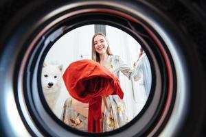 jeune femme à la maison met la robe dans la machine à sécher. photo