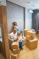 jeune famille heureuse avec enfant déballant des boîtes ensemble assis sur un canapé photo