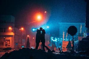 jeune couple adulte dans les bras l'un de l'autre sur la rue couverte de neige. photo