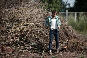 l'homme aux bottes authentiques et aux jeans selvedge sur fond de branches photo