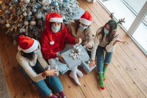 groupe multiethnique d'amis en bonnets de noel avec des cadeaux dans les mains. photo