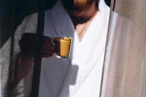 mâle en peignoir blanc avec une tasse de café à la main. photo