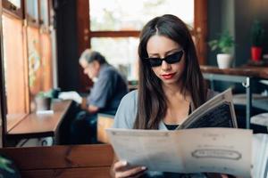 jolie femme à lunettes de soleil est assise dans un restaurant. photo