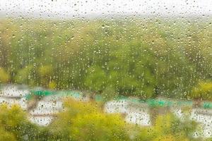 gouttes de pluie sur verre o et jardin de ville flou photo
