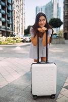 femme élégante avec valise regardant la caméra photo