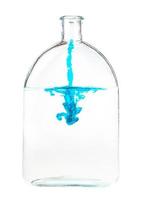 un filet d'encre bleue s'écoule dans l'eau d'un flacon en verre photo