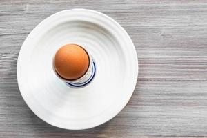 Oeuf brun dans une tasse sur une plaque blanche à bord gris photo