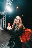 femme blonde avec smartphone la nuit dans la rue. photo