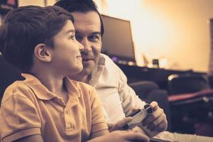 heureux père et fils parlant tout en jouant à des jeux vidéo à la maison. photo