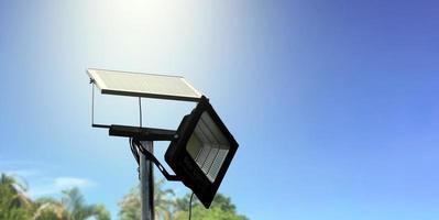 mini panneau de cellules solaires ou photovoltaïques installé sur un poteau métallique avec projecteur led, arrière-plan flou nuageux et bluesky, concept d'utilisation de l'énergie naturelle du soleil dans la vie quotidienne de l'homme. photo