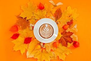 tasse de café au lait dans un cadre de couronne de feuilles d'automne sèches photo