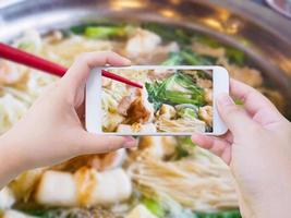 femme prenant une photo de sukiyaki shabu shabu