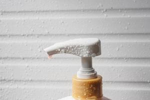 goutte d'eau sur la pompe du distributeur de savon liquide pendant l'heure du bain photo