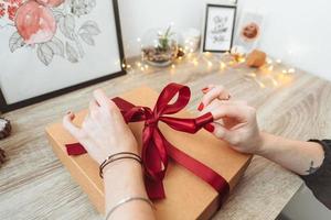 femme emballant présente dans du papier avec ruban rouge. photo