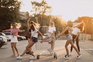 les jeunes femmes avec un chariot de supermarché s'amusent photo