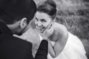 le marié touche doucement le visage de sa mariée photo