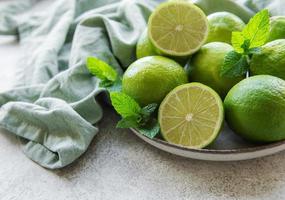 limes vertes avec des feuilles de menthe fraîche sur la plaque photo