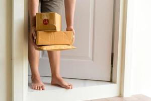 la femme récupère le colis à la porte. boîte près de la porte au sol. achats en ligne, boîtes livrées à votre porte. facile à voler quand personne n'est à la maison. colis sous carton sur le pas de la porte. service de livraison photo