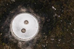 couvercle de trou d'homme de toilette blanc sur l'ancien sol en ciment noir photo