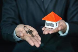 agent immobilier avec modèle de maison et clés, concept d'investissement immobilier. photo