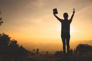 mains d'une femme chrétienne tenant une bible et une croix tout en priant Dieu, croyances religieuses, espace de copie. photo