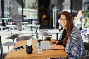 portrait d'une étudiante utilisant un net-book assis dans un café photo