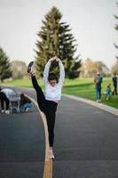 femme en tenue de sport sur la route faisant des divisions debout. photo