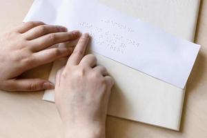 Le bout du doigt d'une femme aveugle lit une note en braille photo