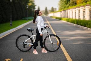 belle fille posant au vélo blanc. marcher dans la nature. photo