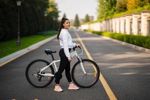 belle fille posant au vélo blanc. marcher dans la nature. photo