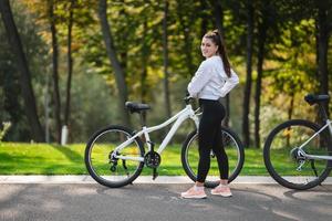 belle fille posant au vélo blanc. marcher dans la nature. photo