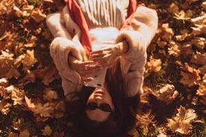 vue de dessus de la belle jeune femme se trouve sur les feuilles d'automne photo