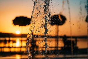 le ruisseau d'une fontaine éclabousse l'eau, le coucher du soleil photo