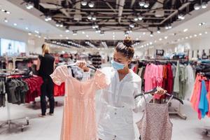 jeune femme faisant du shopping dans une boutique de vêtements avec masque de protection photo