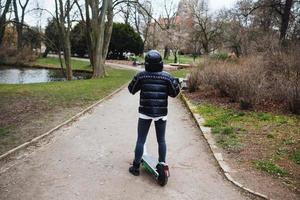 fille moderne chevauchant un scooter électrique écologique dans le parc. photo