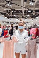 jeune femme faisant du shopping dans une boutique de vêtements avec masque de protection photo