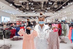 jeune femme faisant du shopping dans une boutique de vêtements avec masque de protection photo