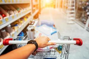 main humaine en gros plan avec un panier dans un supermarché marchant dans l'allée photo