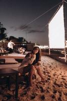 jeune femme est assise sur une chaise à la plage de nuit photo