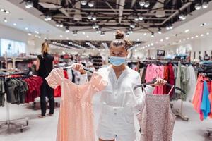 jeune femme faisant du shopping dans une boutique de vêtements avec masque de protection photo