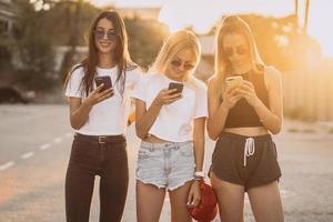 trois jolies femmes se tiennent sur un parking avec des smartphones photo