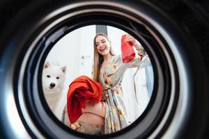 jeune femme à la maison met la robe dans la machine à sécher. photo